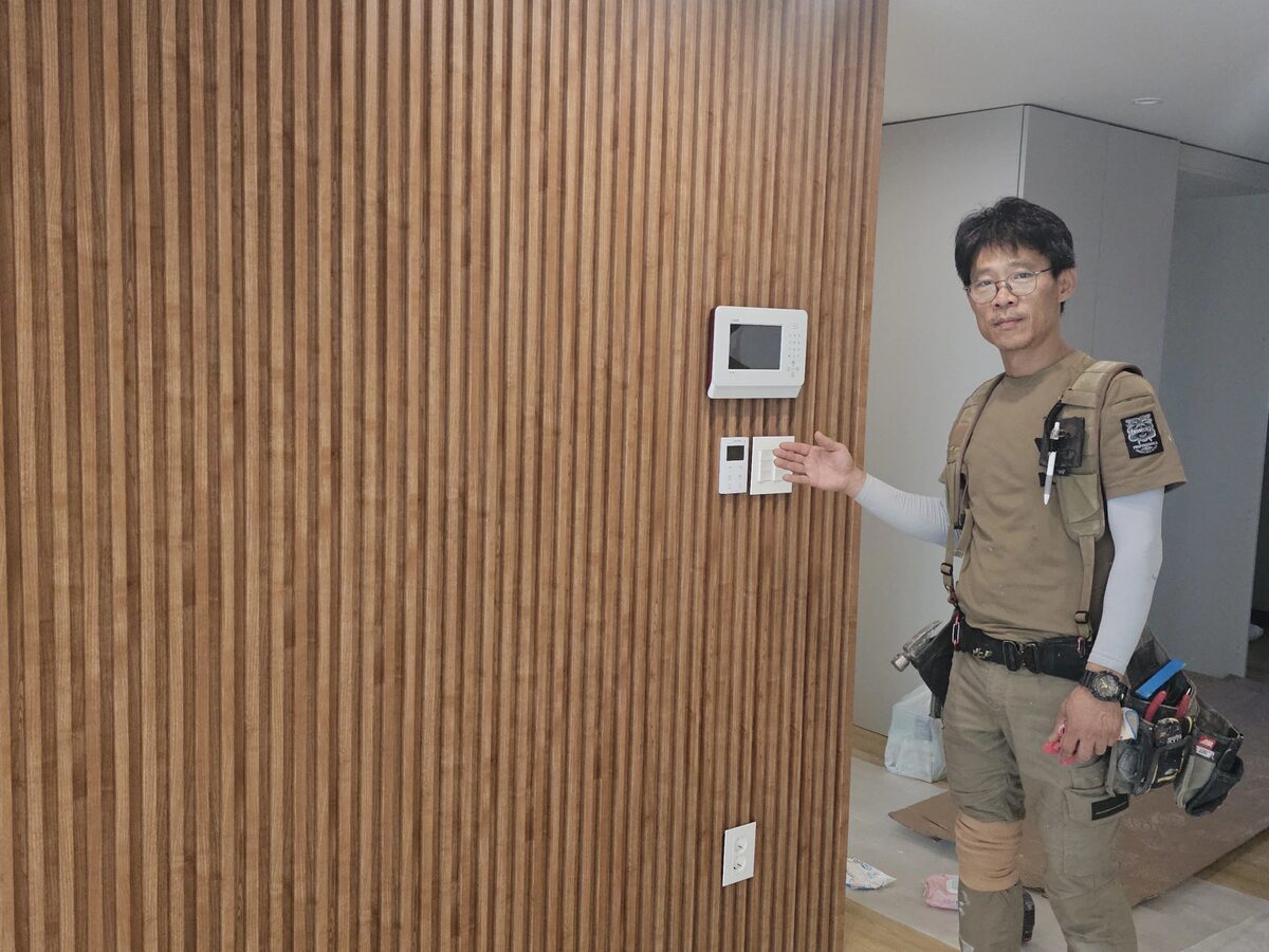 우드슬랫 마감이 끝난 벽에 월패드를 다시 고정하고 확인하는 모습
