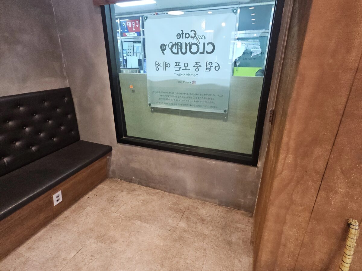 완성된 창가벤치 가죽 쿠션 모서리와 유리창의 카페 상호가 함께 보이는 근접 사진